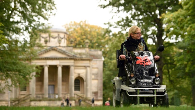 Visitor riding a 'tramper' at Gibside with a neo-classical chapel visible in the background